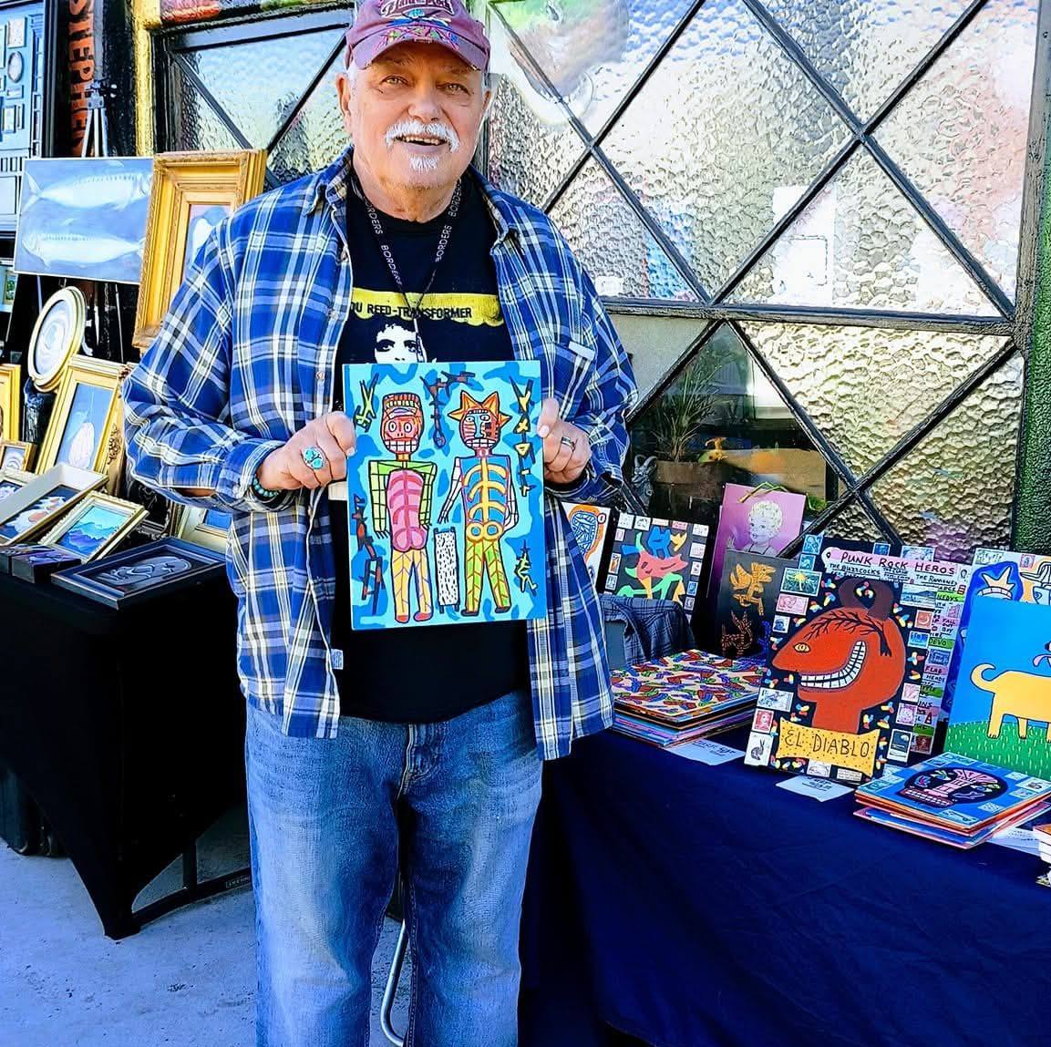 Peter John Geise standing with a display of his artwork